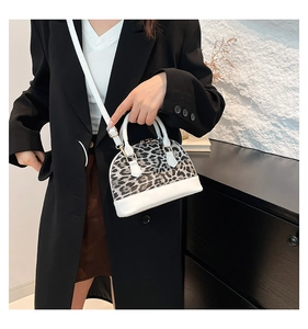 Detail of stylish leopard print shell bag with white leather straps and gold hardware