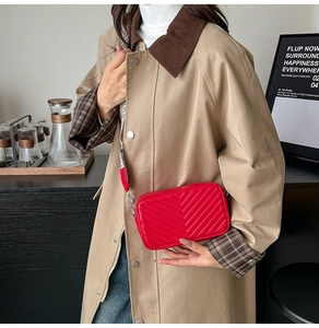 Détail du sac bandoulière rouge matelassé avec large sangle à damier noir et blanc