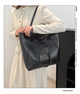 Gros plan d'un sac cabas noir à motif crocodile porté par un mannequin pour le travail