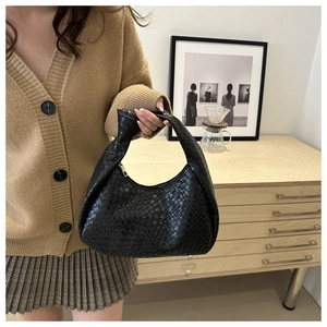 Detail of black woven texture hobo bag featuring a knotted handle and metal zipper