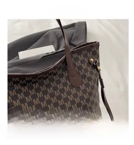 Close-up of vintage brown tote bag with M-letter monogram print and metal rivets