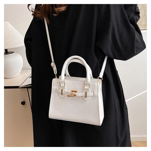 Detail of white tote bag featuring golden hardware locks and detachable shoulder strap