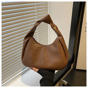 Close-up of woven checkerboard texture and knotted strap on dark brown hobo bag