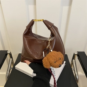 Dark brown glossy shoulder bag with logo embossing and a cute teddy bear charm