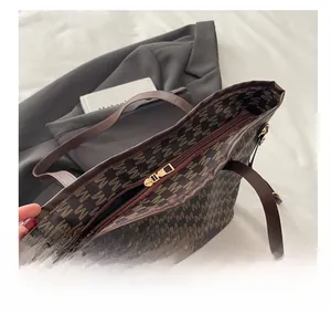 Close-up of smooth metal zipper and printed monogram pattern on brown tote bag