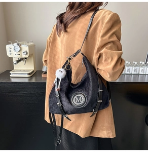 Détail du sac hobo en velours noir avec logo M et porte-clés peluche sur un modèle