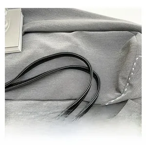 Détail des doubles bretelles en cuir noir avec texture fine et surpiqûres blanches
