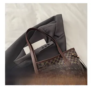 Close-up of vintage printed tote bag with M-pattern texture and brown leather straps