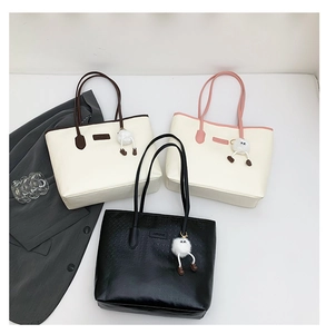 Detail view of large tote bags in three colors with litchi texture and plush charm