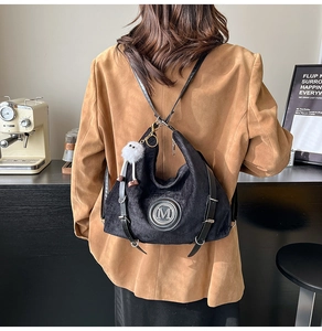 Vue détaillée du sac cabas en velours côtelé noir avec logo M et pompon blanc doux