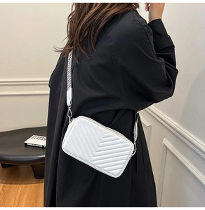 Détail du sac bandoulière blanc matelassé avec une large sangle en tissu à motifs
