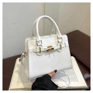 Detail of white textured handbag showing gold metal twist lock and durable top handle