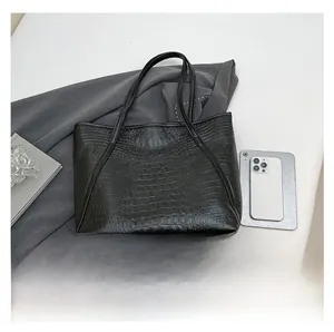 Gros plan détaillé du sac cabas noir à motif crocodile avec smartphone pour l'échelle