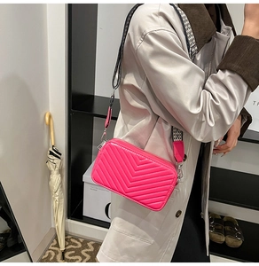 Détail d'un sac à bandoulière matelassé rose avec une sangle à carreaux noir et blanc