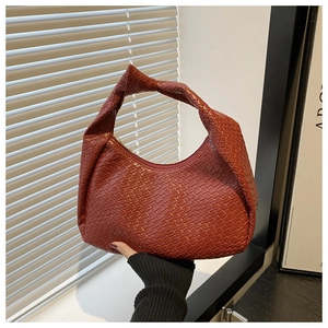 Close-up of woven brick red hobo bag featuring a knotted handle and metallic zipper