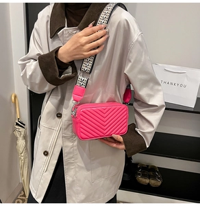 Détail du sac photo matelassé rose vif avec large bandoulière à motifs géométriques