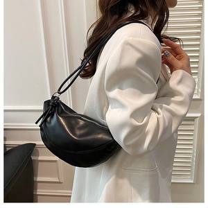 Minimalist black crescent shoulder bag featuring knotted strap and sleek faux leather finish