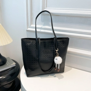 Black houndstooth tote bag with plush charm on table, elegant office shoulder handbag