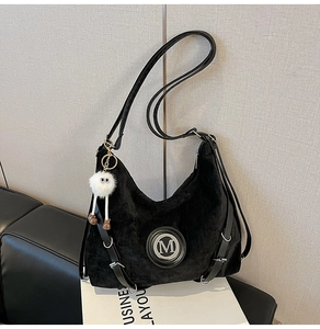Détail du sac à épaule en velours noir avec logo M argenté et boucles élégantes