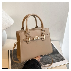 Detail of light beige top-handle tote with metal lock closure and adjustable shoulder strap