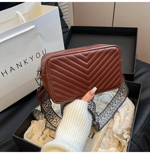 Détail du sac en cuir marron foncé avec surpiqûres en V et large bandoulière géométrique