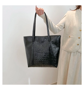 Détail du sac cabas noir à motif crocodile avec de longues bandoulières fines en cuir