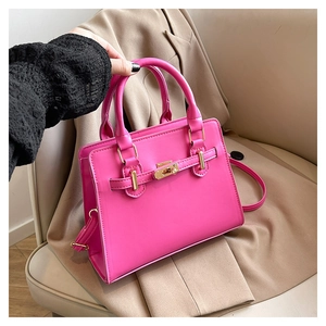 Detail of hot pink structured handbag with gold hardware and smooth leather finish