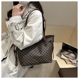 Macro detail of large tote bag with M-letter monogram pattern and brown leather straps