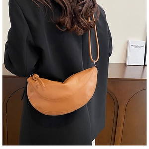 Detail showing the knotted strap connection on a brown crescent shoulder bag for women