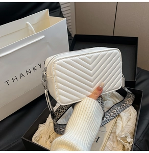 Détail d'un sac à bandoulière blanc en similicuir matelassé avec large sangle tissée