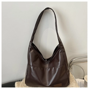 Dettaglio borsa shopper vintage marrone scuro in pelle PU su sfondo di maglia beige