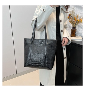 Détail du sac cabas noir à motif crocodile montrant la texture brillante et l'espace utile