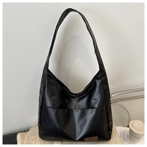 Dettaglio ravvicinato di una borsa tote nera con un'etichetta decorativa in pelle marrone