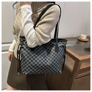 Close-up of a large tote bag featuring vintage M-pattern monogram and side leather straps