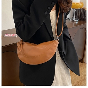 Close-up of minimalist brown crescent shoulder bag on a model wearing a black blazer