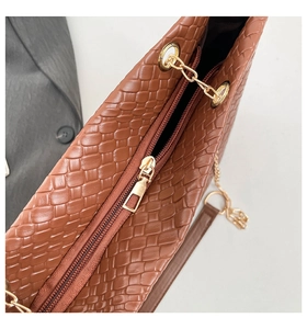 Close-up of brown woven texture PU leather handbag with golden metal zipper and chain detail