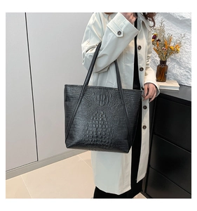 Gros plan détaillé du sac cabas noir motif crocodile avec logo rond en relief sur le cuir