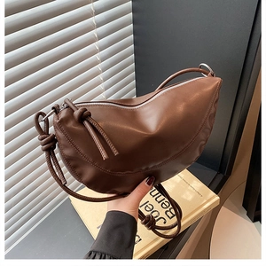 Detail of a dark brown hobo bag featuring a knotted shoulder strap and silver zipper closure