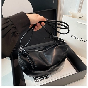 Detailed view of black crescent bag featuring knot strap and premium leather texture