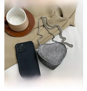 Macro detail of heart-shaped mini rhinestone bag showing metallic chain and compact size