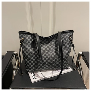 Detailed macro view of monogram print on large tote bag with elegant gold hardware