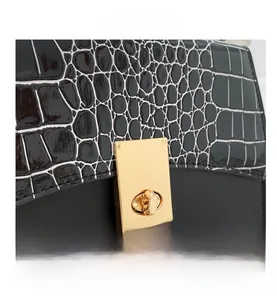 Détail du sac à main avec motif crocodile noir et blanc et fermoir rotatif en métal doré