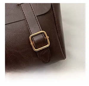 Detail of dark brown lychee texture leather backpack with a golden metal square buckle