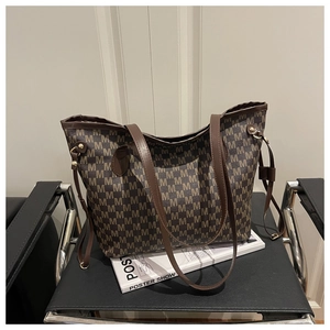 Detail of monogram print tote bag with brown leather straps and gold hardware accents