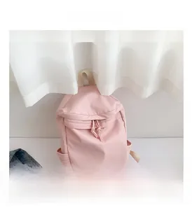 Detail view of pink nylon backpack with drawstring closure and side pockets for women
