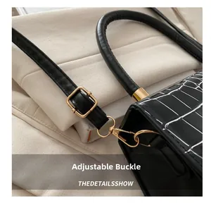 Détail du sac en cuir noir à motif crocodile avec boucle dorée et surpiqûres