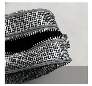 Close-up showing the secure black zipper closure on a silver rhinestone heart evening bag