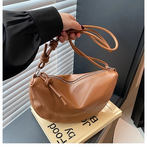 Detail shot of caramel crescent handbag with stylish knotted strap and zip closure