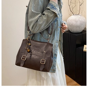 Detail of vintage dark brown faux leather bag with embossed logo and metal bell charm