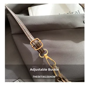 Détail de la bandoulière réglable avec boucle dorée sur un sac cabas en cuir marron foncé
